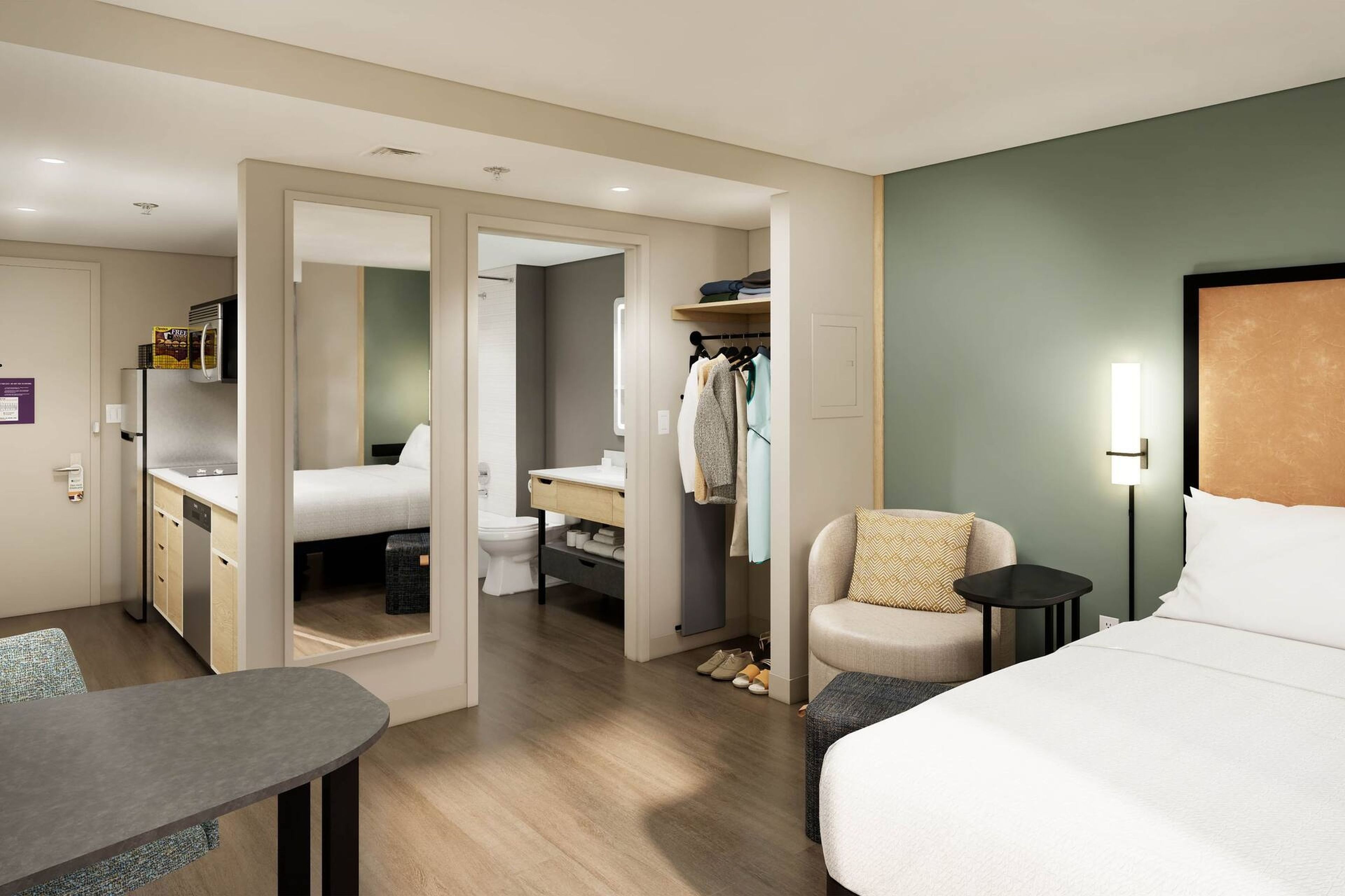 Une chambre d’hôtel comprenant un lit, un bureau, une chaise, une petite table, une armoire et une salle de bain.
