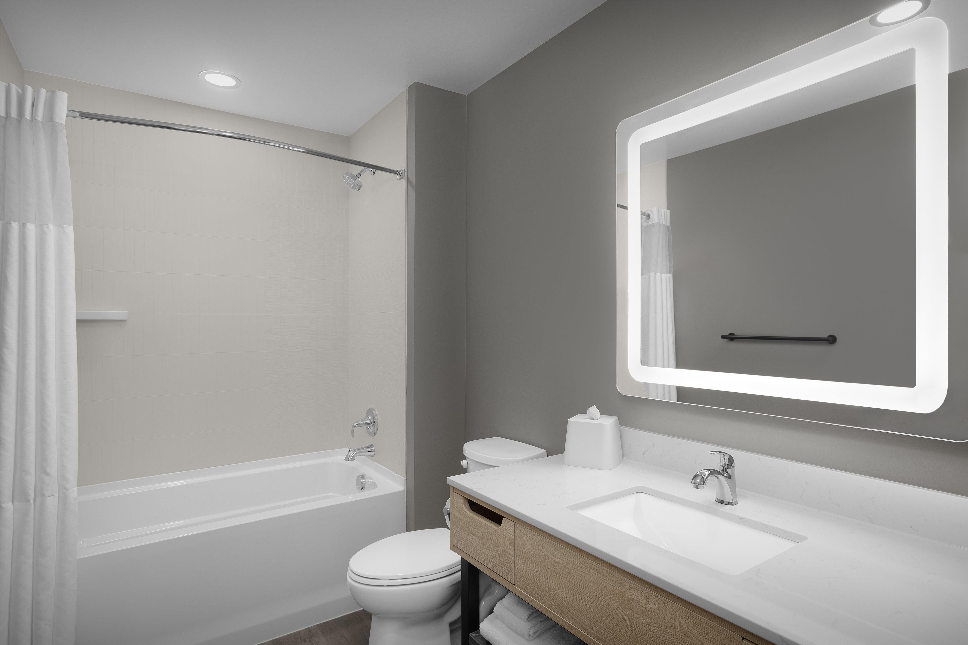 A modern bathroom with a bathtub, toilet, and vanity.