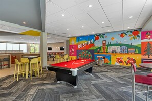 A pool table in a brightly lit indoor space with a mural on the wall.