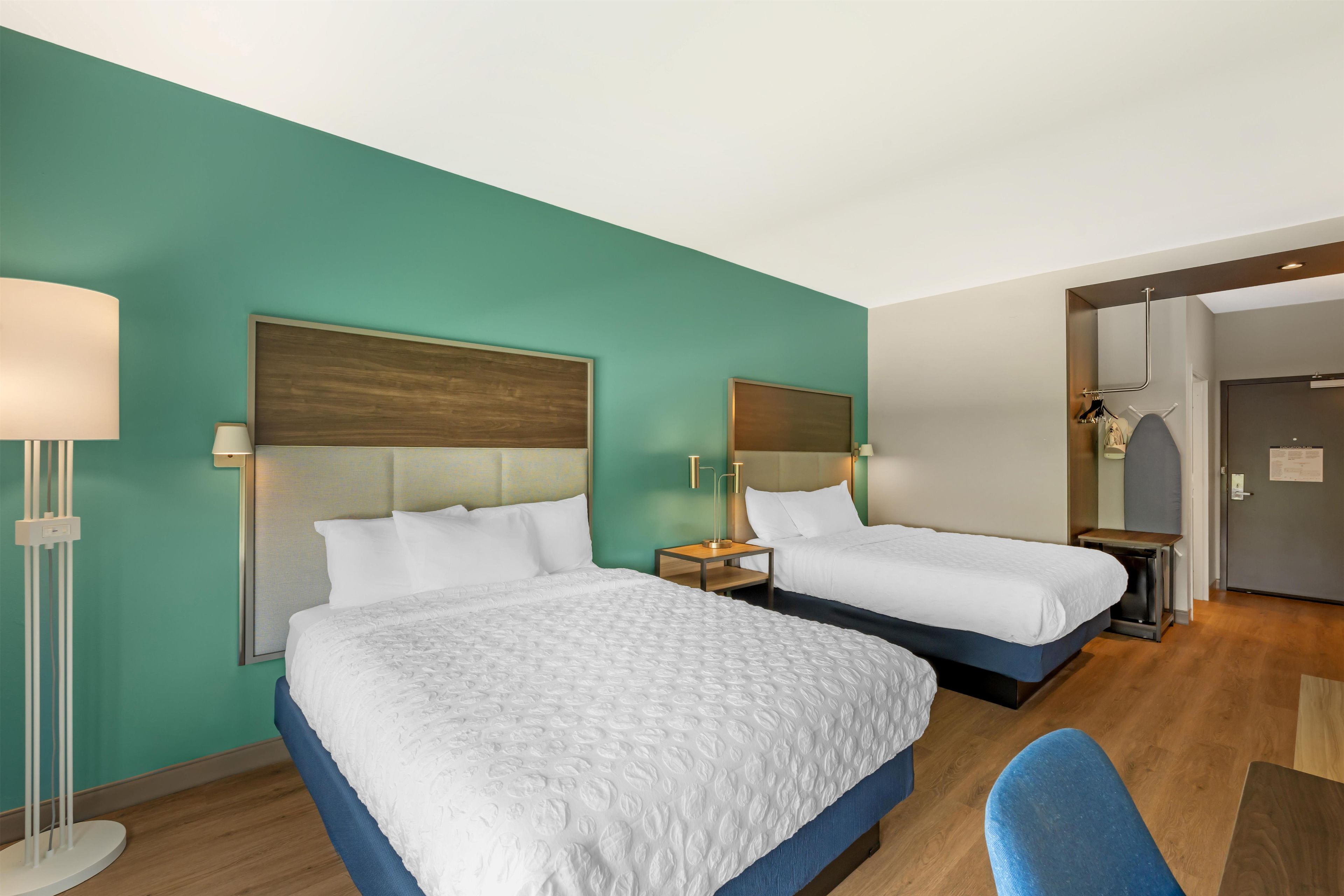 Habitación de hotel con dos camas, un escritorio, una silla y un armario.