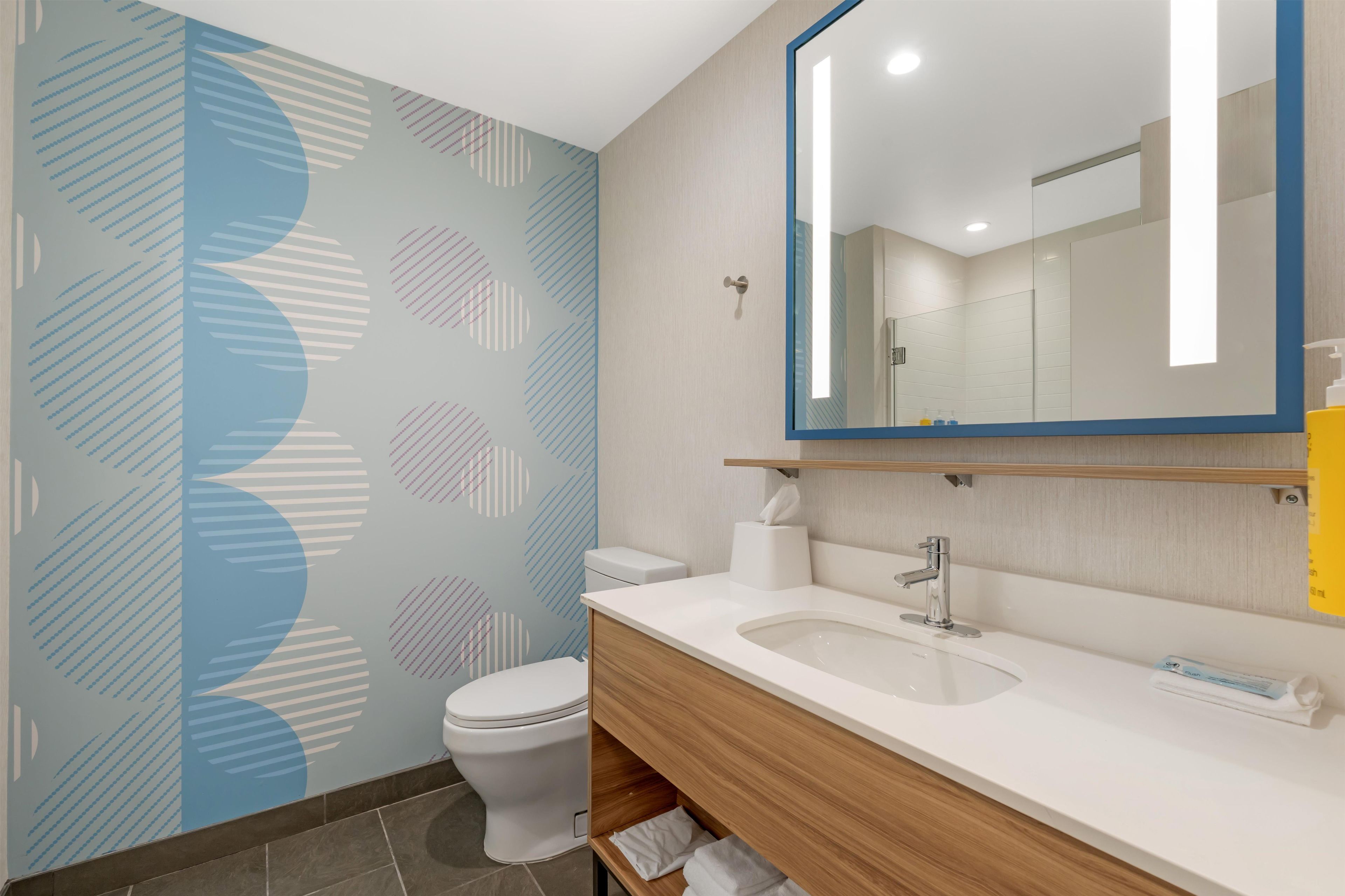 Ein modernes Badezimmer mit Toilette, Waschbecken und Spiegel.