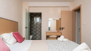 A modern hotel room with a bed, a bedside table, a mirror, and a bathroom visible through an open door. - Villy Suites II - Zante Lux Suite Near the Beach (Zakynthos)