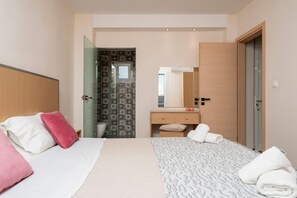 Ein modernes Hotelzimmer mit Bett, Nachttisch, Spiegel und einem durchgegangenen Tür sichtbaren Badezimmer.