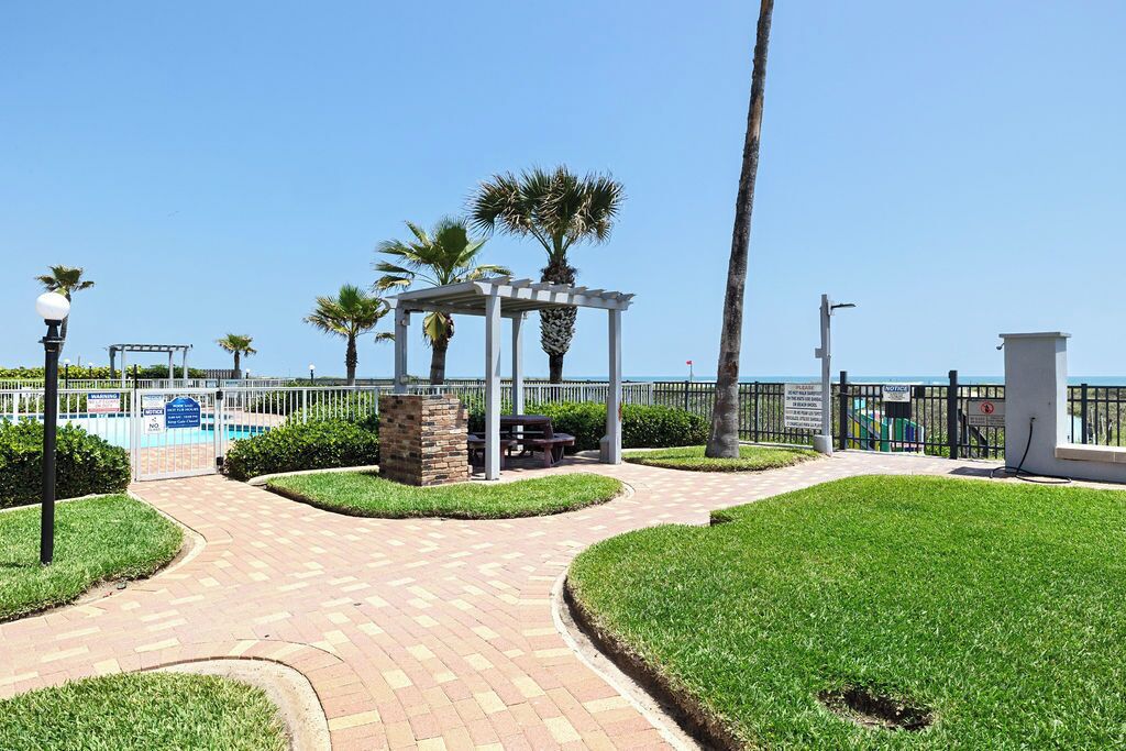 A paved walkway, a gazebo, palm trees, and a pool area.