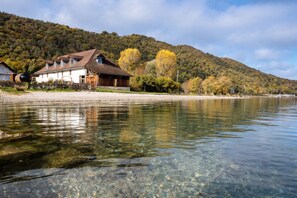 Ein Anwesen am Seeufer mit einem Haus, klarem Wasser und einem bewaldeten Hügel.