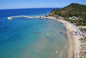 A coastal beach with clear waters, a rocky breakwater, and a hilly backdrop. - Villy Suites I - Zante Luxury Suite With Hot Tub (Zakynthos)