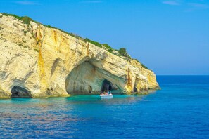 A coastal cliff with a boat in the water, a clear sky, and a calm sea. - Villy Suites I - Zante Luxury Suite With Hot Tub (Zakynthos)