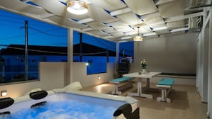 Une salle de spa moderne équipée d’un jacuzzi, d’un coin salon et d’une table agrémentée d’une plante en pot.