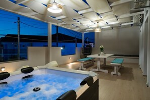 Ein moderner Wellnessraum mit Whirlpool, Sitzgelegenheit und einem Tisch mit einer Topfpflanze.