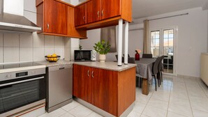 Une cuisine moderne avec des meubles en bois, un four à micro-ondes, un four traditionnel et un coin repas comprenant une table et des chaises.
