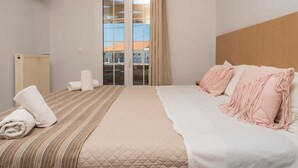 Une chambre d’hôtel avec un lit, un radiateur, une télévision et une porte-fenêtre coulissante.