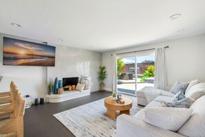 A modern living room with a fireplace, a large window, and a view of the outdoors. - Harbor Isle Beauty - Minutes To Huntington Beach (Huntington Beach)