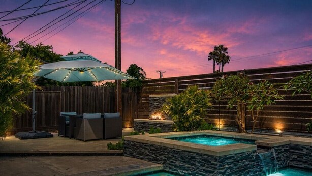 A backyard with a swimming pool, a covered seating area, and a stone wall. - Harbor Isle Beauty - Minutes To Huntington Beach (Huntington Beach)