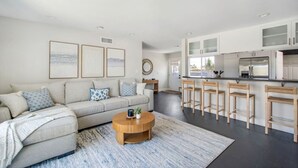 A modern living room with a sofa, coffee table, and artwork on the wall. - Harbor Isle Beauty - Minutes To Huntington Beach (Huntington Beach)