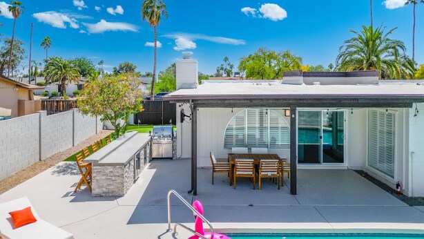 Eine moderne Außenpatio mit Pool, Sitzgelegenheiten und einem überdachten Bereich mit Tisch und Stühlen.