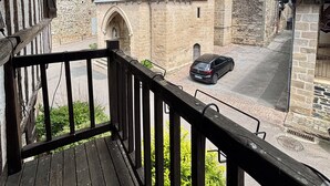 A stone building with a tower, a car parked in front, and a wooden balcony.