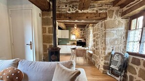 A cozy room with a sofa, a fireplace, and a kitchen in the background.