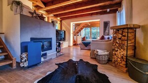 Ein geräumiges Wohnzimmer mit Kamin, einer Couch, einem Fernseher und einer Holztreppe.