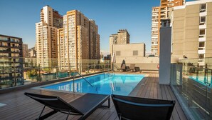 A rooftop pool with lounge chairs, surrounded by high-rise buildings. - Downtown Suites by Andes+ (Santiago)