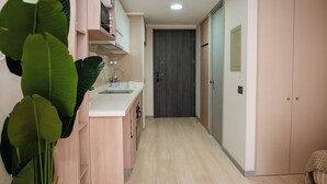 A narrow hallway with a kitchen area on the left, a dark door at the end, and a wardrobe on the right. - Downtown Suites by Andes+ (Santiago)