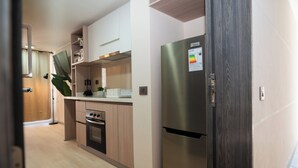 A modern kitchen with stainless steel appliances, wooden cabinets, and a built-in oven. - Downtown Suites by Andes+ (Santiago)