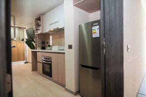 A modern kitchen with stainless steel appliances, wooden cabinets, and a built-in oven. - Downtown Suites by Andes+ (Santiago)