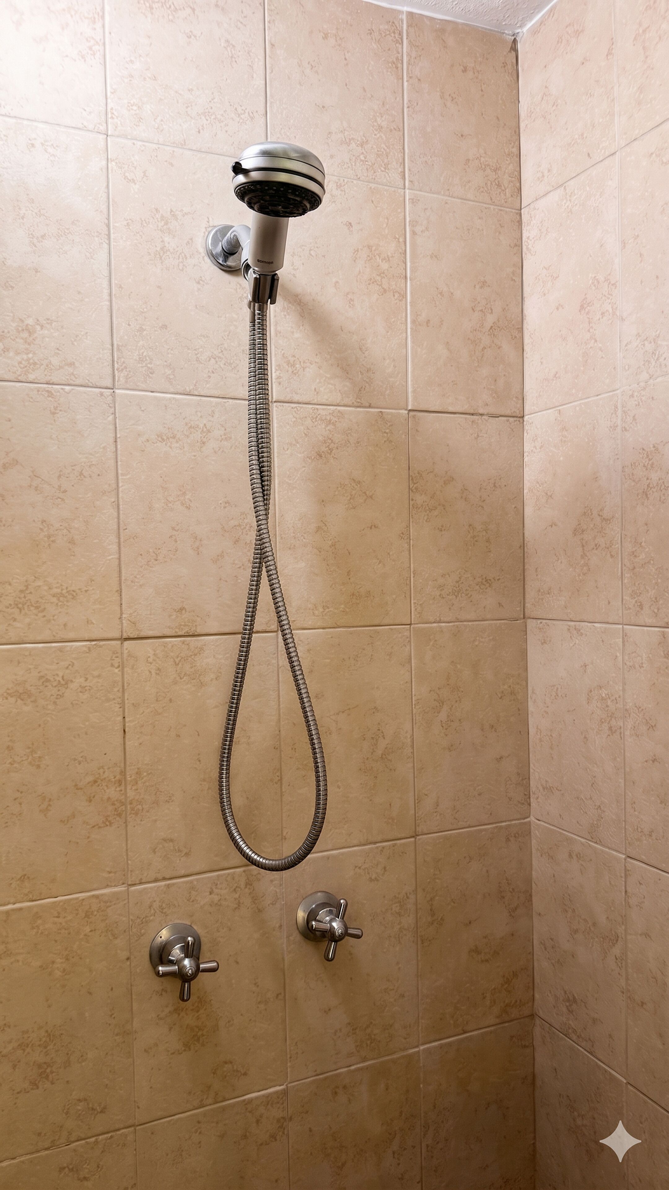 A shower with a handheld showerhead and two wall-mounted controls.
