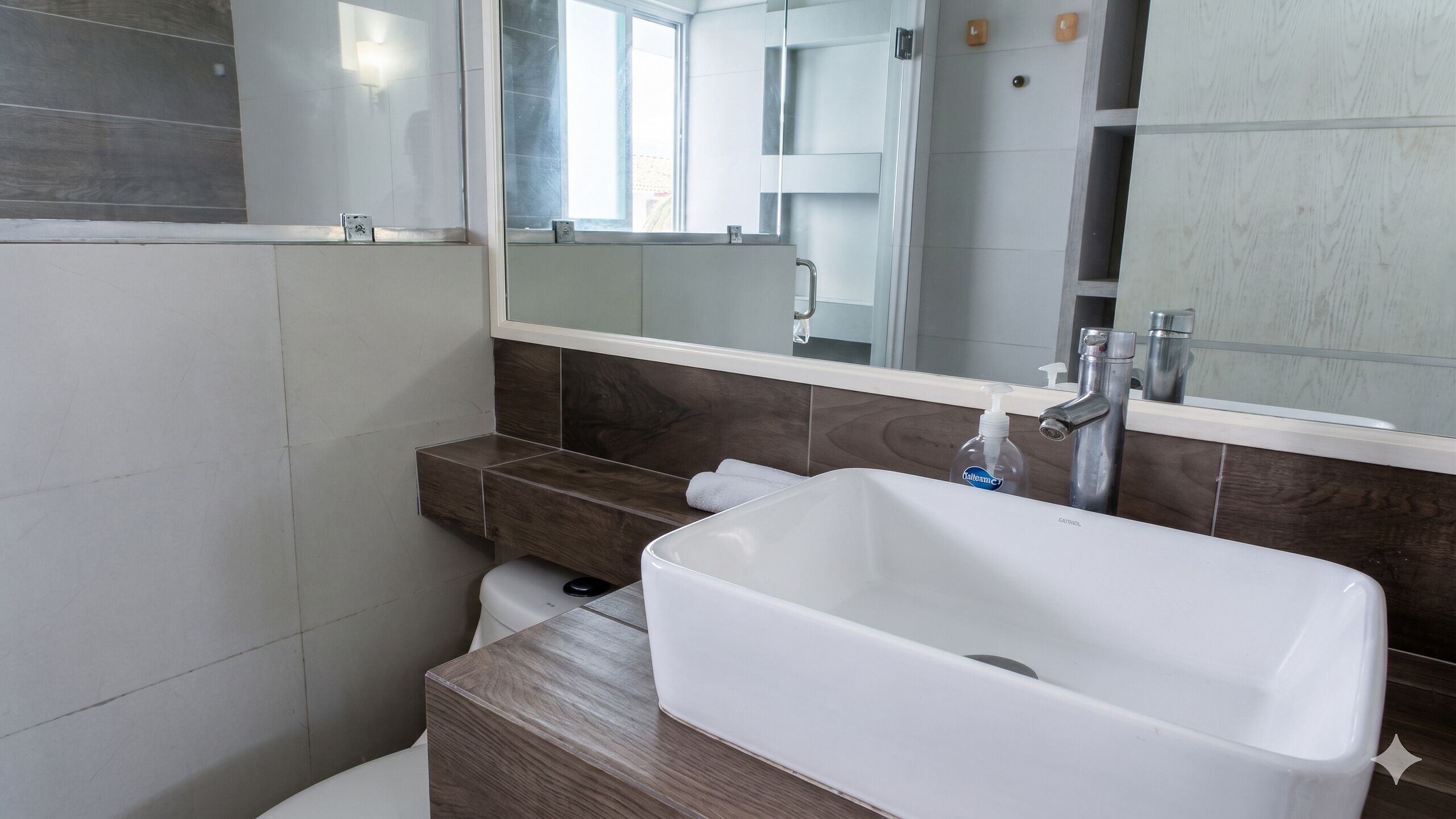 Un bagno con lavandino bianco, uno specchio e un dispenser per asciugamani.