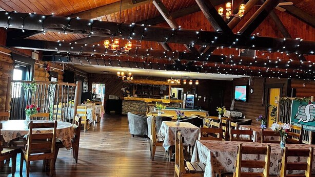 Un intérieur rustique avec des poutres en bois, des guirlandes lumineuses et des tables recouvertes de nappes à motifs floraux.