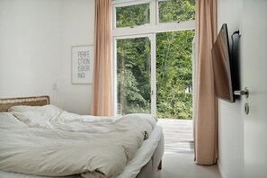Ein Schlafzimmer mit einem Bett, einem Vorhangfenster, einem an der Wand montierten Fernseher und einem Schild mit Text.