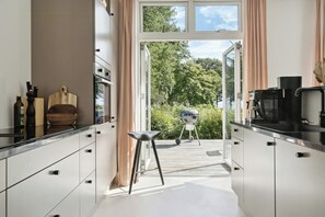 Eine moderne Küche mit Blick ins Freie, ein Barhocker und ein Grill.