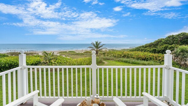 A balcony with a view of the ocean and beach, white railings, and a table with a basket and cups. - 1045 Wave Crest Avenue (Indialantic)