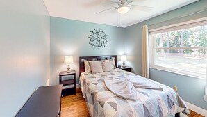 Ein Schlafzimmer mit einem Bett, Nachttischen, einem Deckenventilator und einem Fenster mit Blick.