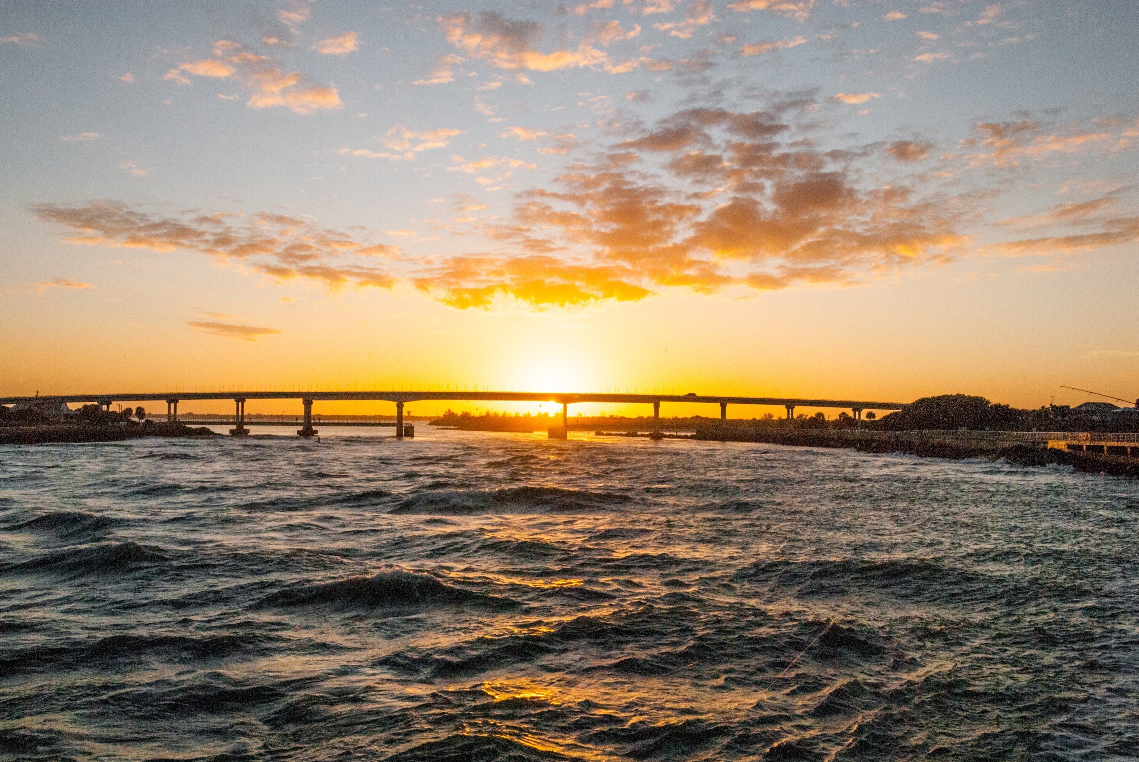 A sunset over a bridge with water below.