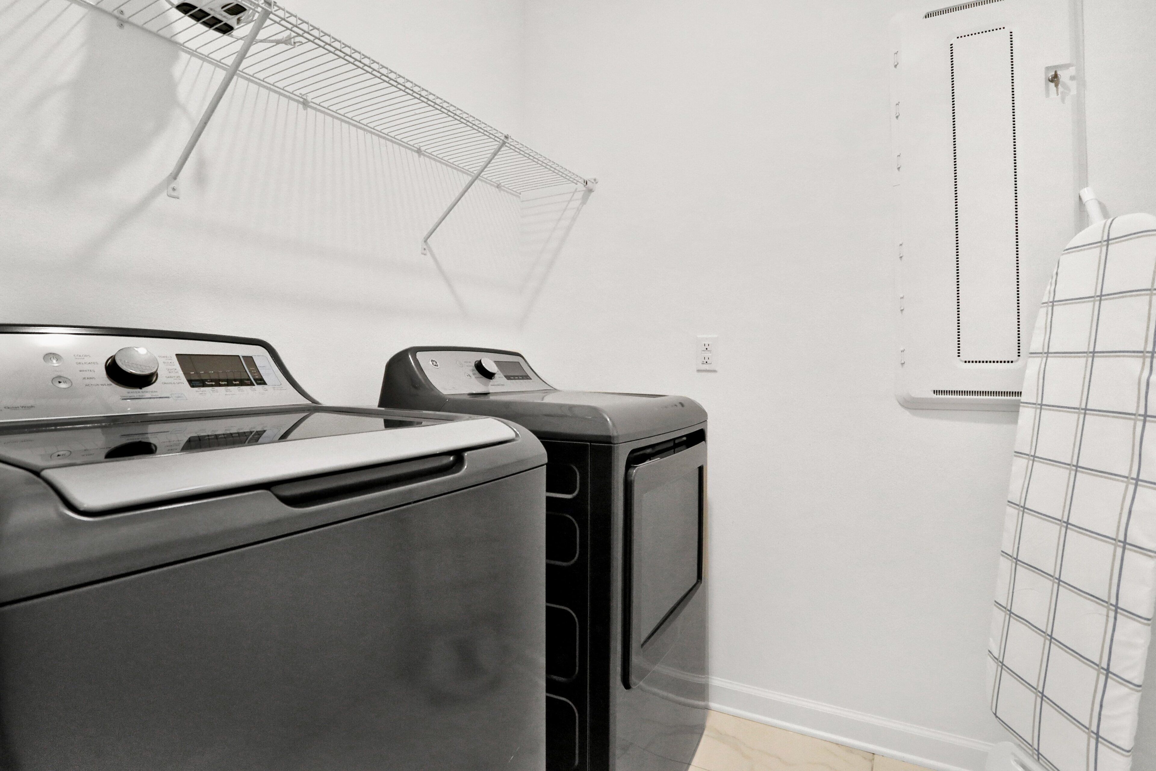 A laundry room with two washing machines and a drying rack.