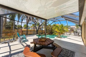Um alpendre coberto com piscina, móveis de madeira e vista para a região.