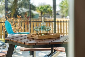 Ein Holztisch für ein Picknick mit einer Flasche und zwei Gläsern auf einer Ablagefläche.