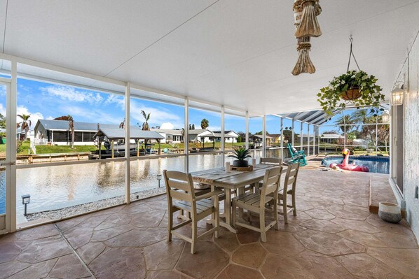 A covered patio with a table and chairs, a hanging plant, a pool, and a view of the surrounding area. - 1480 W Riviera Dr (Merritt Island)