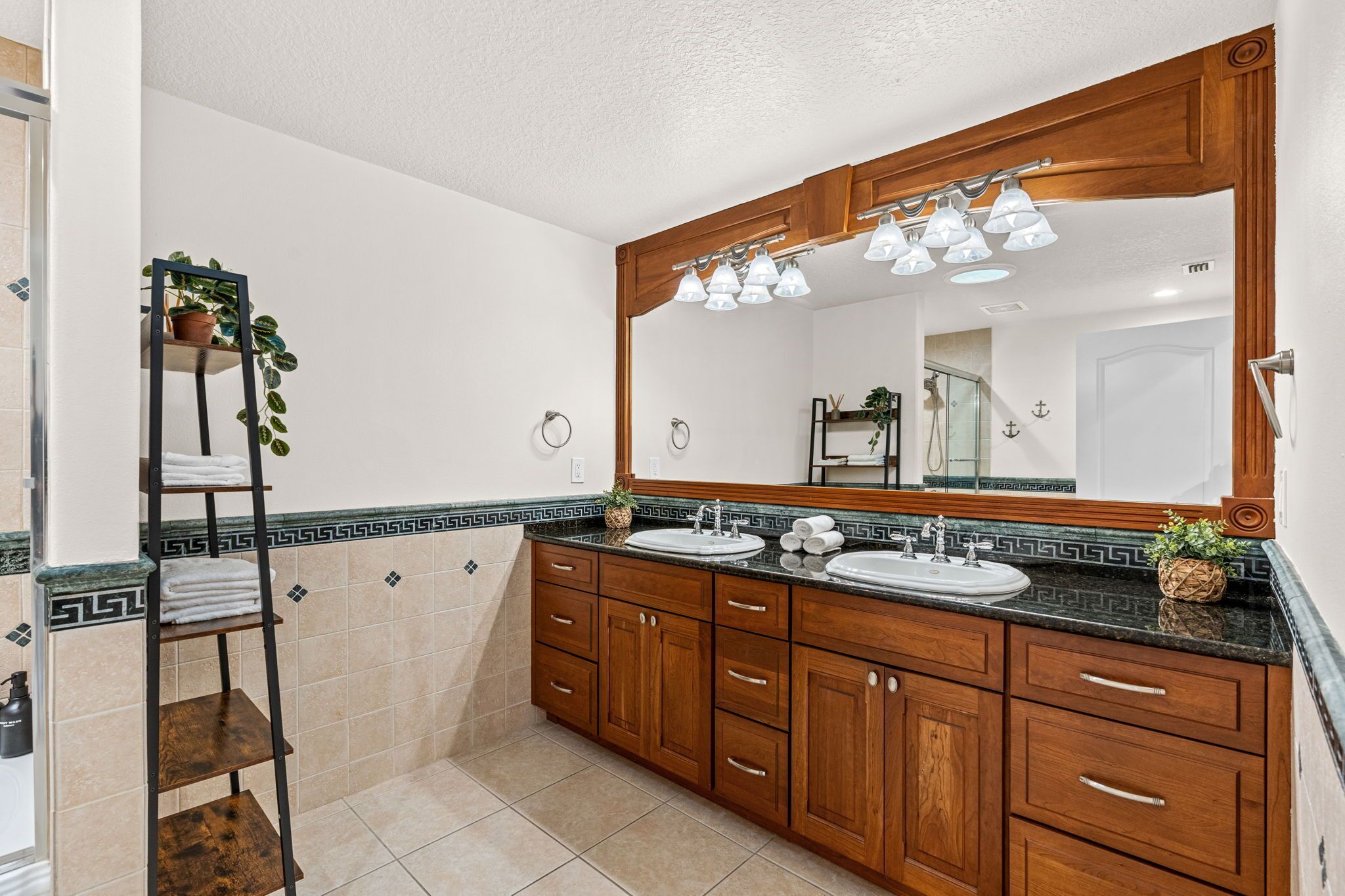 A bathroom with wooden cabinets, a large mirror, two sinks, and a towel rack.