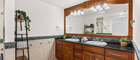 A bathroom with wooden cabinets, a large mirror, two sinks, and a towel rack.