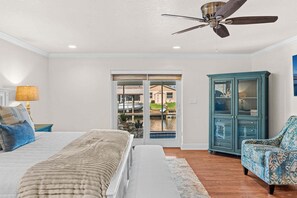 A bedroom with a bed, a ceiling fan, a cabinet, and a view through a glass door. - 1480 W Riviera Dr (Merritt Island)