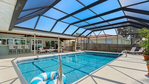 Una piscina interna con soffitto in vetro, sedie a sdraio e un’area bar.