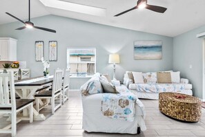 A spacious living area with a dining table, two sofas, a coffee table, and ceiling fans. - 206 Ocean View Lane (Indialantic)