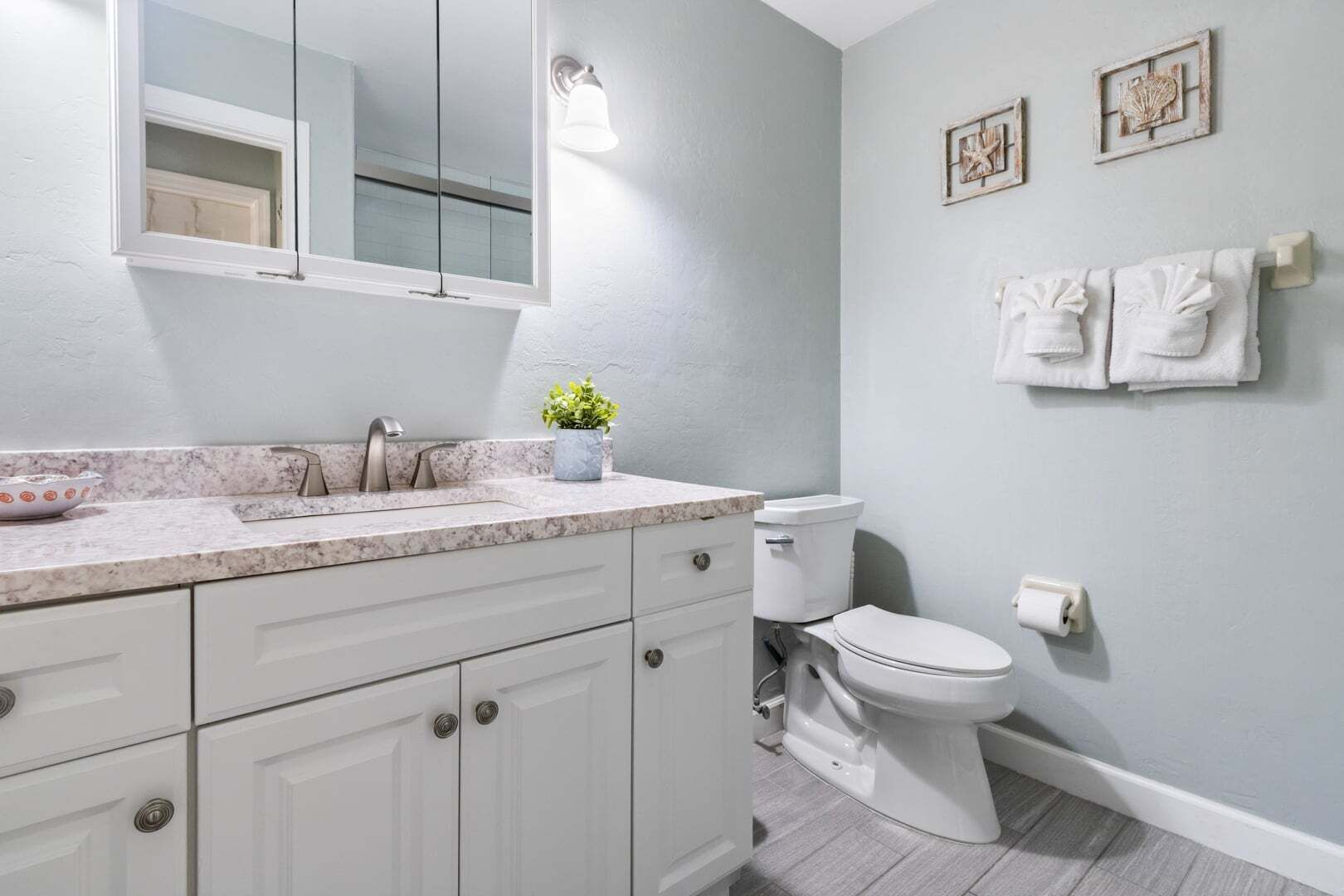 A bathroom with a white sink, a mirror, a toilet, and a towel rack.
