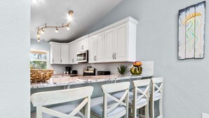 A kitchen with white cabinets, a marble countertop, and a hanging light fixture.
