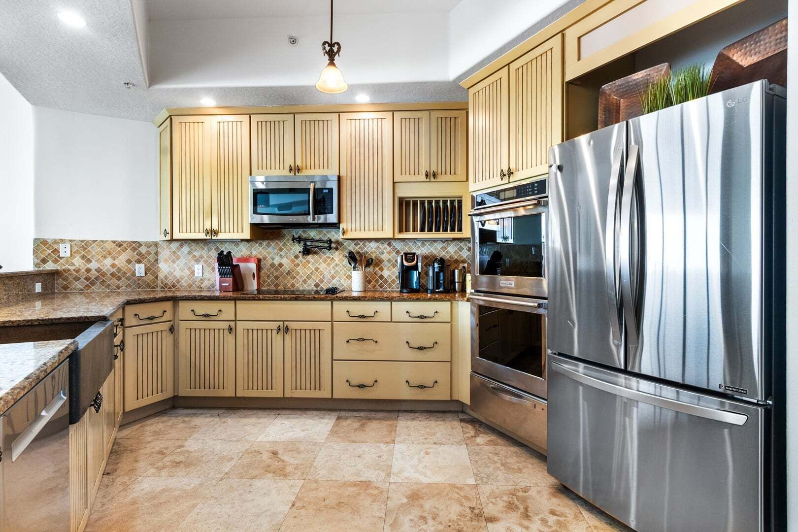 A modern kitchen with a stainless steel refrigerator, double ovens, a microwave, and wooden cabinets.