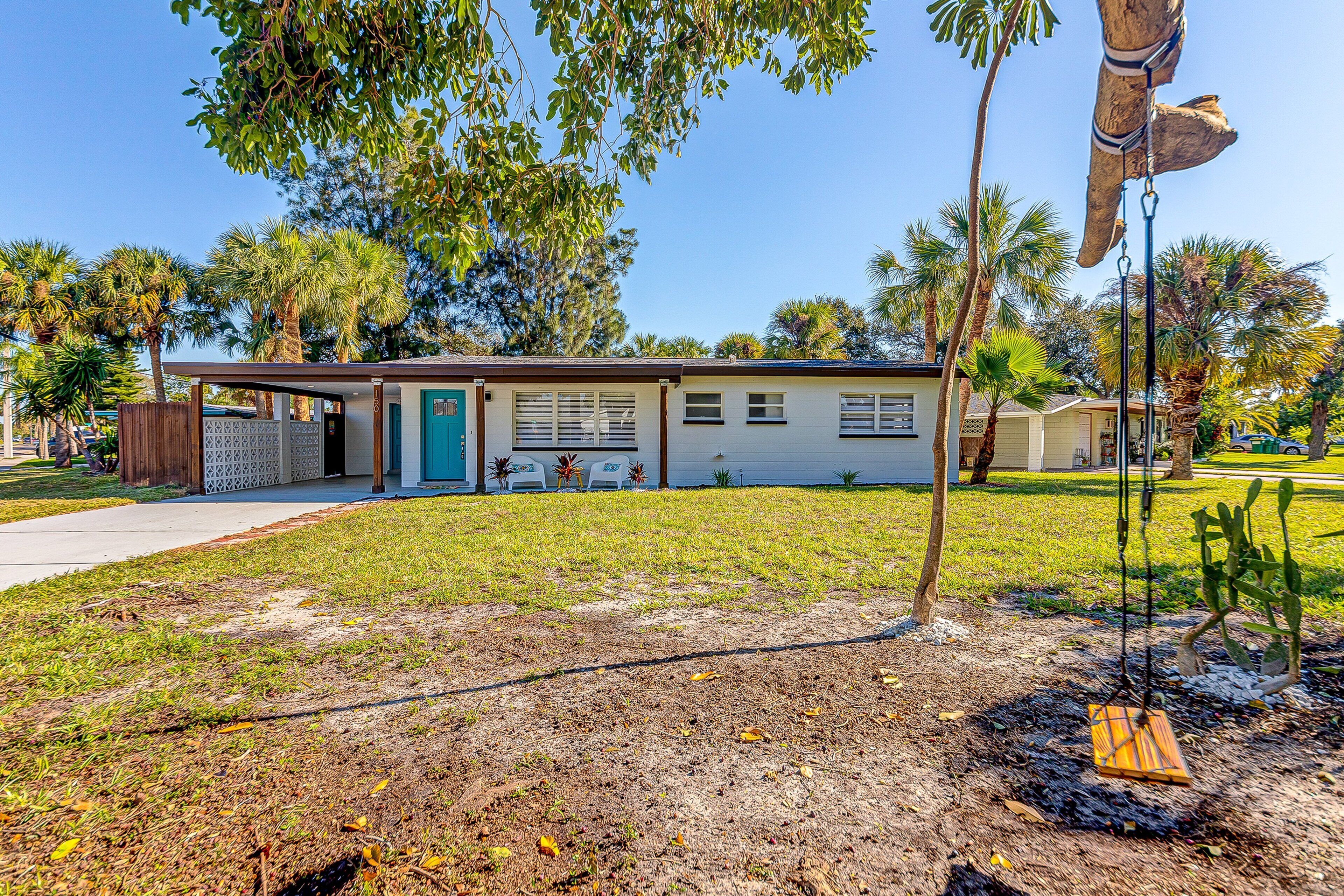 A single-story house with a front porch, a swing set, and a lawn.