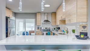 Een moderne keuken met een groot kookeiland, houten kastjes en roestvrijstalen apparatuur, inclusief een inbouwoven.