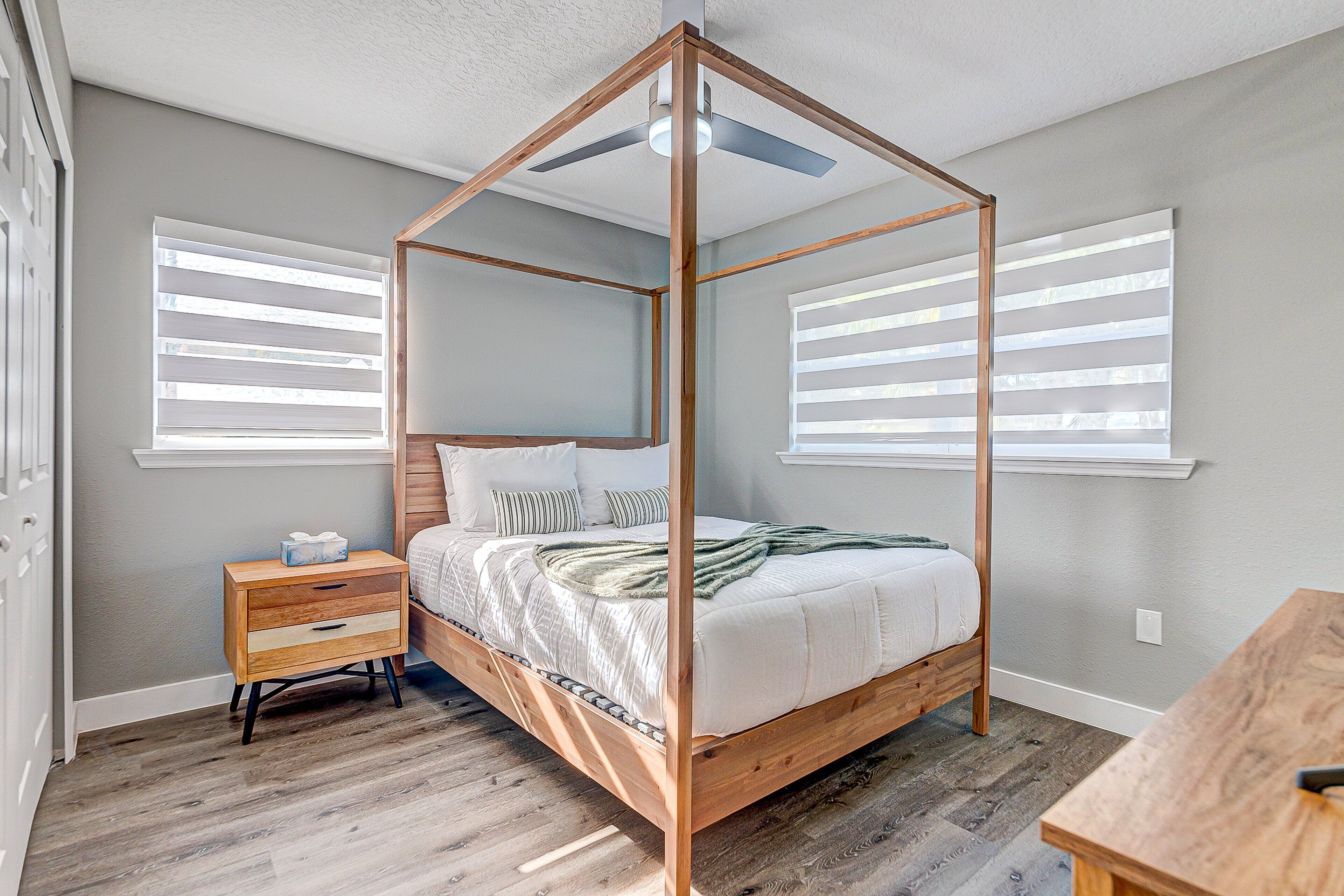 Quarto com cama de dossel, mesa de cabeceira de madeira e uma pequena mesa.