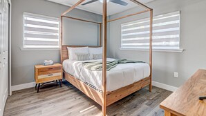 Een slaapkamer met een hemelbed, een nachtkastje van hout en een klein tafeltje.